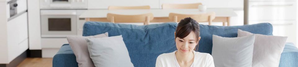 A young woman using a laptop that is sitting on a coffee table